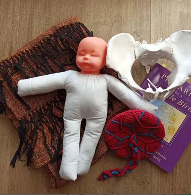 Pomôcky na predpôrodnú prípravu — látková panenka, model panvy a šatka rebozo